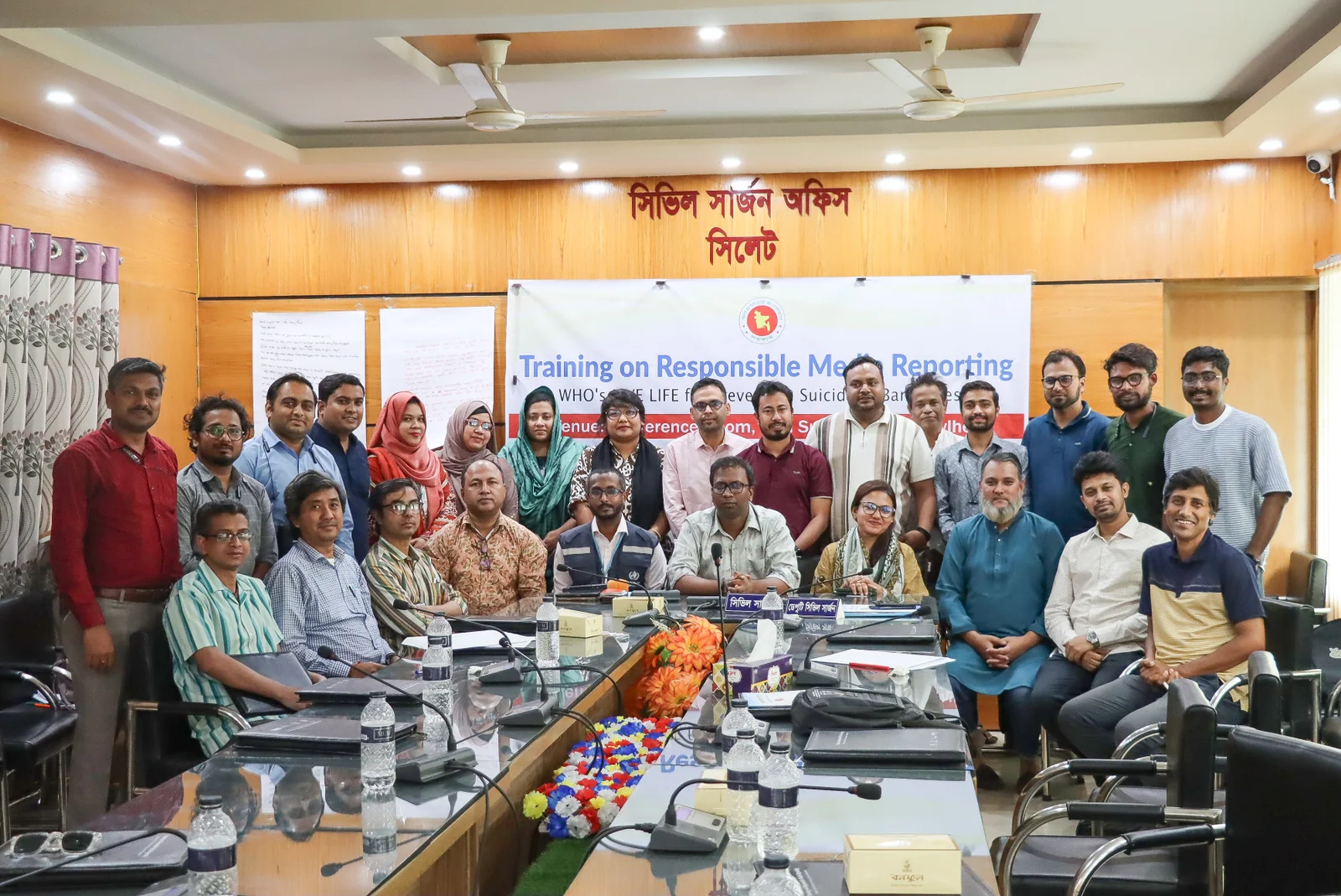 Participants grouped for a photograph beneath a banner reading Training on Responsible Media Reporting: WHO's LIVE LIFE for Preventing Suicide in Bangladesh, at the Civil Surgeon's Office in Sylhet